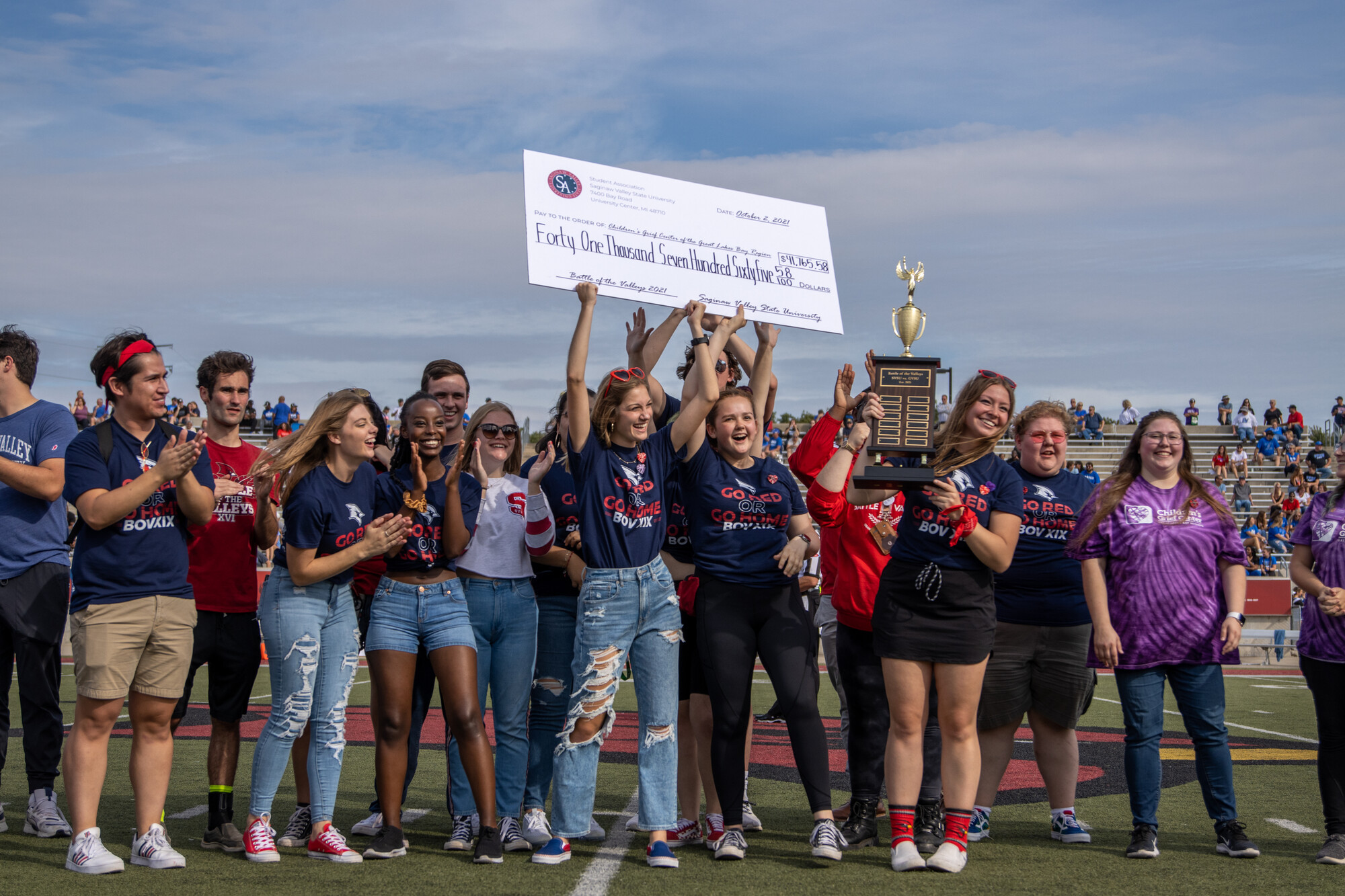 group of students holding giant check above heads